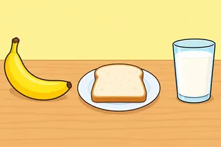 A yellow banana, a slice of bread on a white plate and a glass of milk on a wooden table.